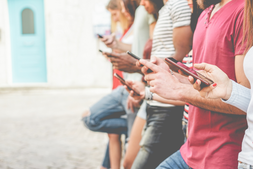 A groupd of people is holding a smartphone in their hands.