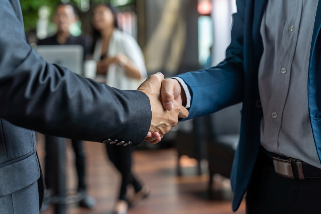 Two men in business outfits are shaking hands.