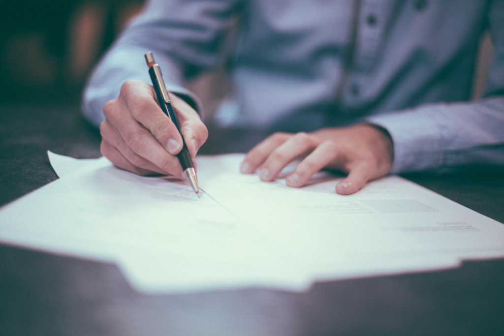 A person is sitting at a desk signing some papers.