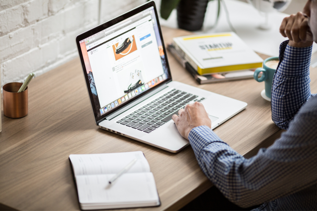 A man is sitting at a desk in front of a laptop reviewing a presentation.