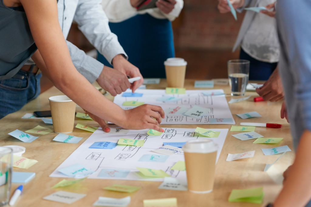 A group of people is brainstorming and putting sticky notes on sheets of paper.