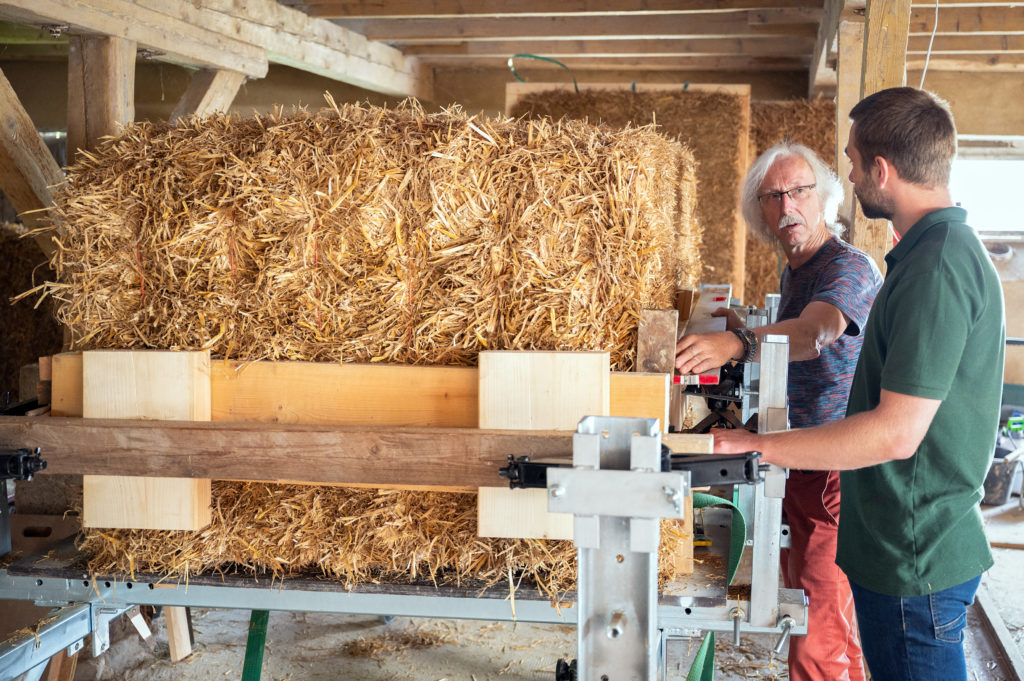 Werner Ehrich and Tim Junghanns are preparing the straw bales for their tiny house made of straw.